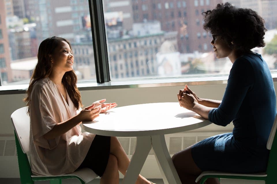Duas pessoas conversando sobre um projeto em uma mesa de reunião